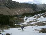 Wide shot of Stephen crossing a small snow field on the way to our camp.  Lake Washington in the background.
